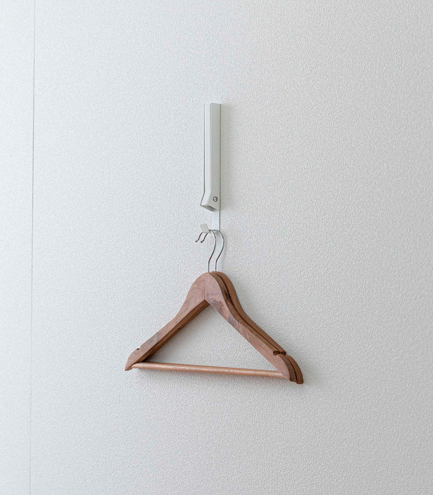 View 18 - White Yamazaki Home Folding Over-The-Door Hanger mounted closed with hangers hung