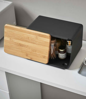 Top-down side view of black Yamazaki Bread Box with Cutting Board Lid partially open view 12
