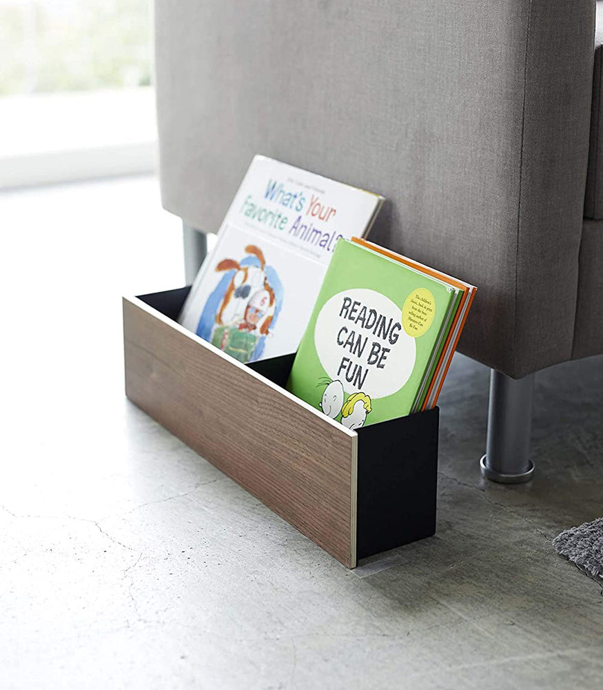 View 21 - Side view of black Desk Organizer on floor holding children's books in living room by Yamazaki Home.
