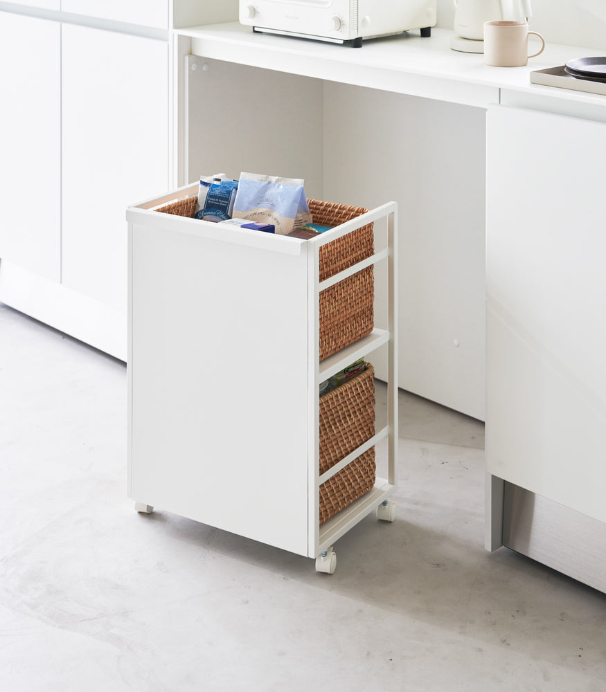 View 7 - Two-level white steel storage cart with casters is shown in an opening of a recessed cabinet. Cart houses storage bins on both levels. One side of the cart has a wall to hide storage.