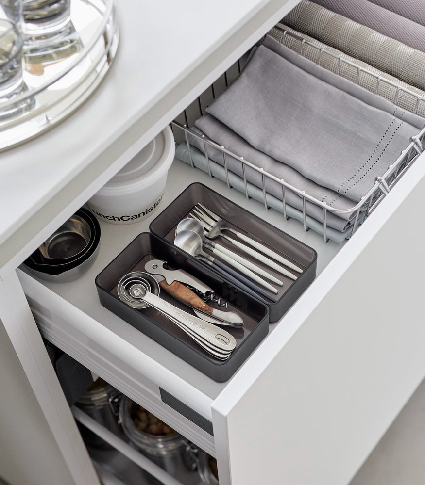 View 24 - Two medium stackable clear organizers in black are placed in a kitchen drawer, organizing cutlery and wine openers, neatly placed next to each other