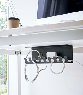 Under-Desk Cable Organizer in black by Yamazaki Home mounted under the desk holding a power strip. view 11