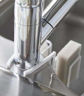 Close up of back of white Steel Yamazaki Home Faucet-Hanging Sponge & Brush Holder attached to a faucet view 6