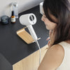 Someone storing a hair dryer on an ash Yamazaki Home Hair Dryer and Iron Stand