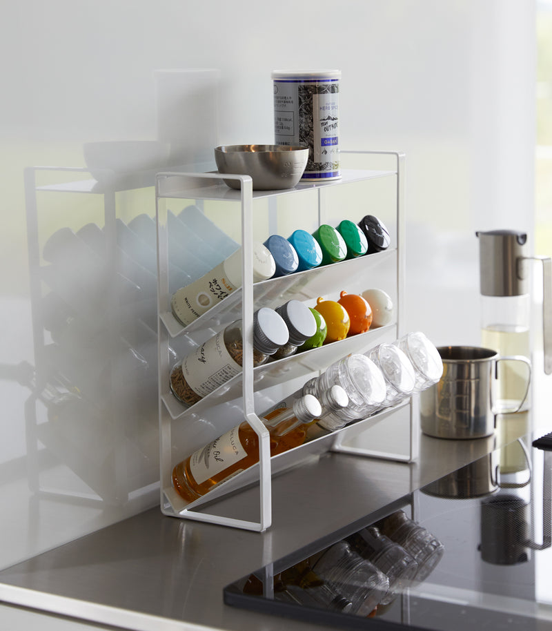 White Four-Tier Slim Spice Rack by Yamazaki Home in a well-lit kitchen, equipped with a variety of spices and essentials.