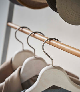 Close up of clothes hung on white Yamazaki Home Coat Rack with Hat Storage view 8