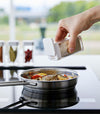 White Yamazaki Home Spice Jar being used to season food in a pan