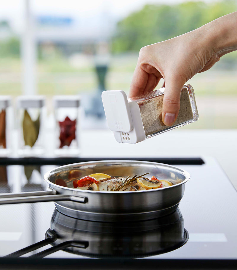 White Yamazaki Home Spice Jar being used to season food in a pan