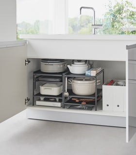 Two of Yamazaki Home Black Three-Tier Cabinet Storage Rack holding pots and pans under the kitchen sink. view 11