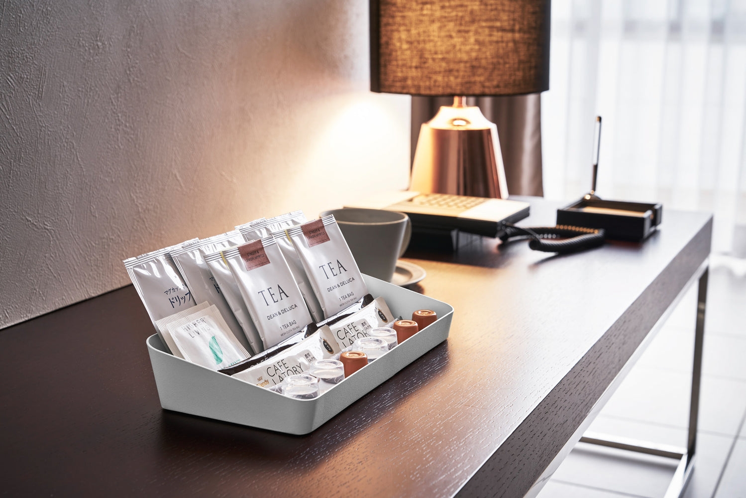 View 13 - Side view of white Accessory Tray holding tea bags and espresso pods on desk by Yamazaki Home.