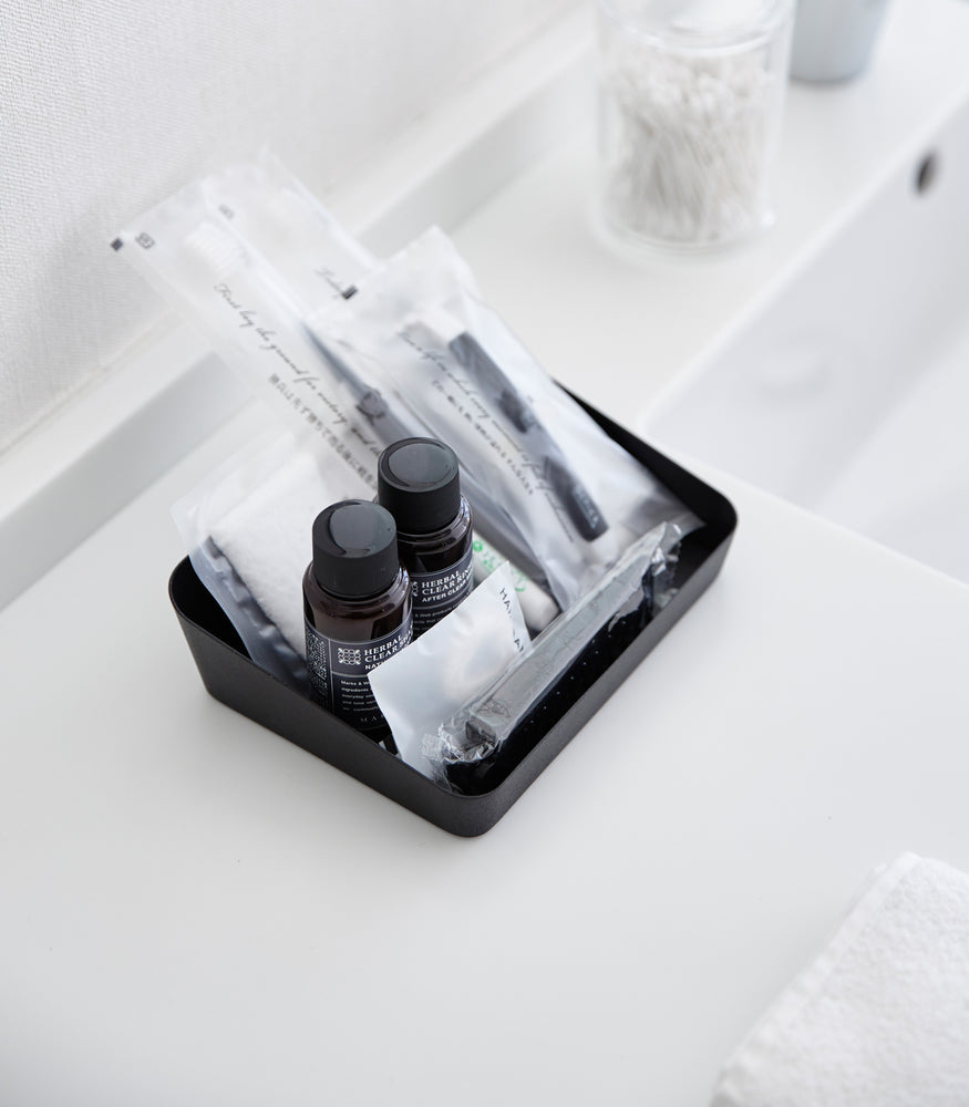 View 8 - Aerial view of medium black Accessory Tray holding beauty items on bathroom sink counter by Yamazaki Home.