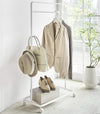 White Rolling Coat Rack holding clothes and fashion accessories by Yamazaki Home.