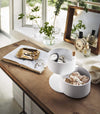 White 2-Tier Stacked Jewelry Box holding jewelry and accessories on vanity by Yamazaki Home.