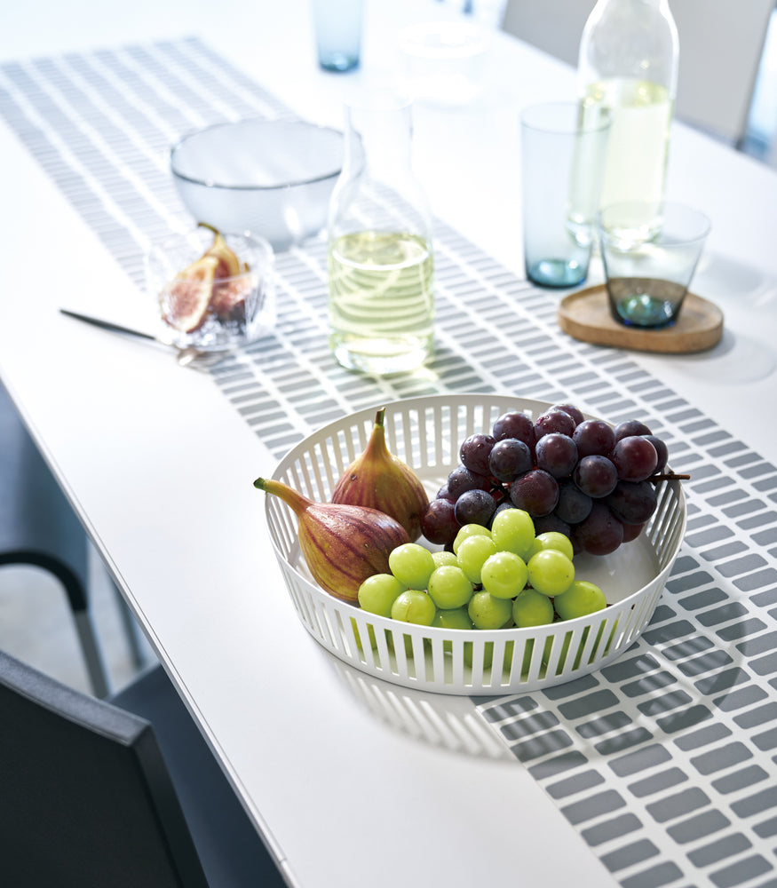 View 3 - White Fruit Basket holding figs and grapes on dining table by Yamazaki Home.