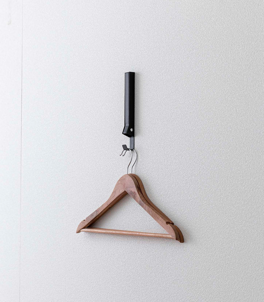 View 26 - Black Yamazaki Home Folding Over-The-Door Hanger mounted closed with hangers hung