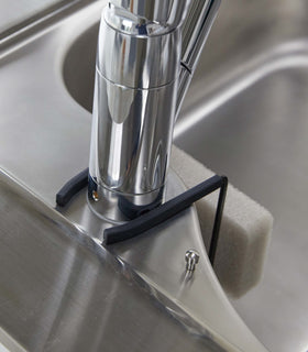 Close up view of black Faucet-Haning Sponge Holder attatched to sink faucet by Yamazaki Home. view 8
