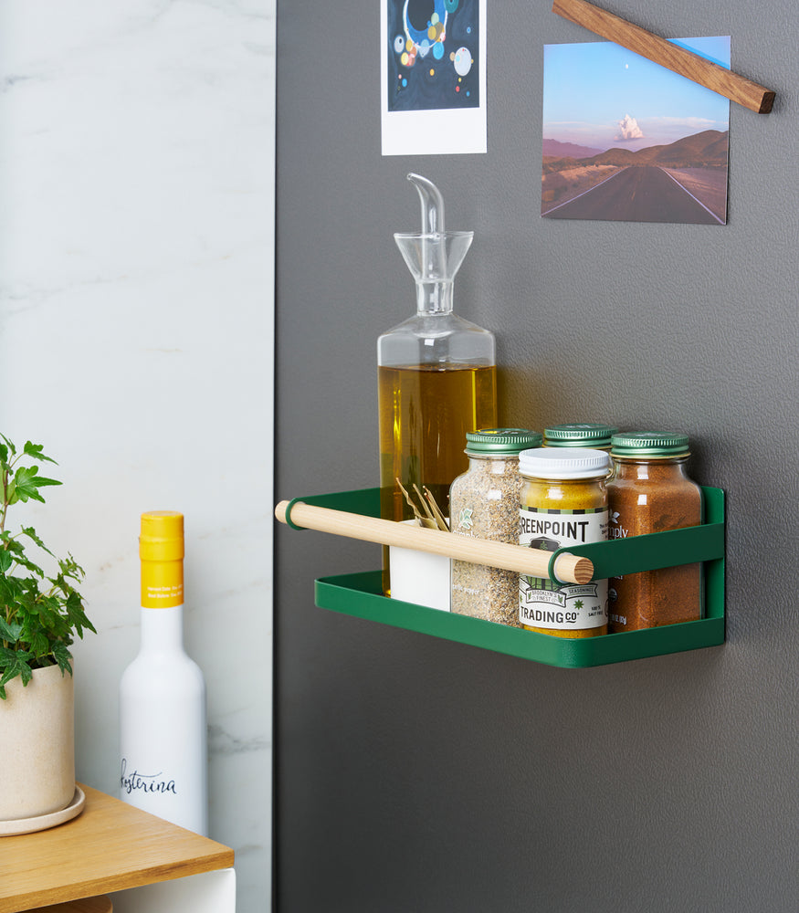 View 4 - Side view of Forest Green Yamazaki Home Magnetic Storage Caddy with oil, herbs and spices stored attached to a refridgerator