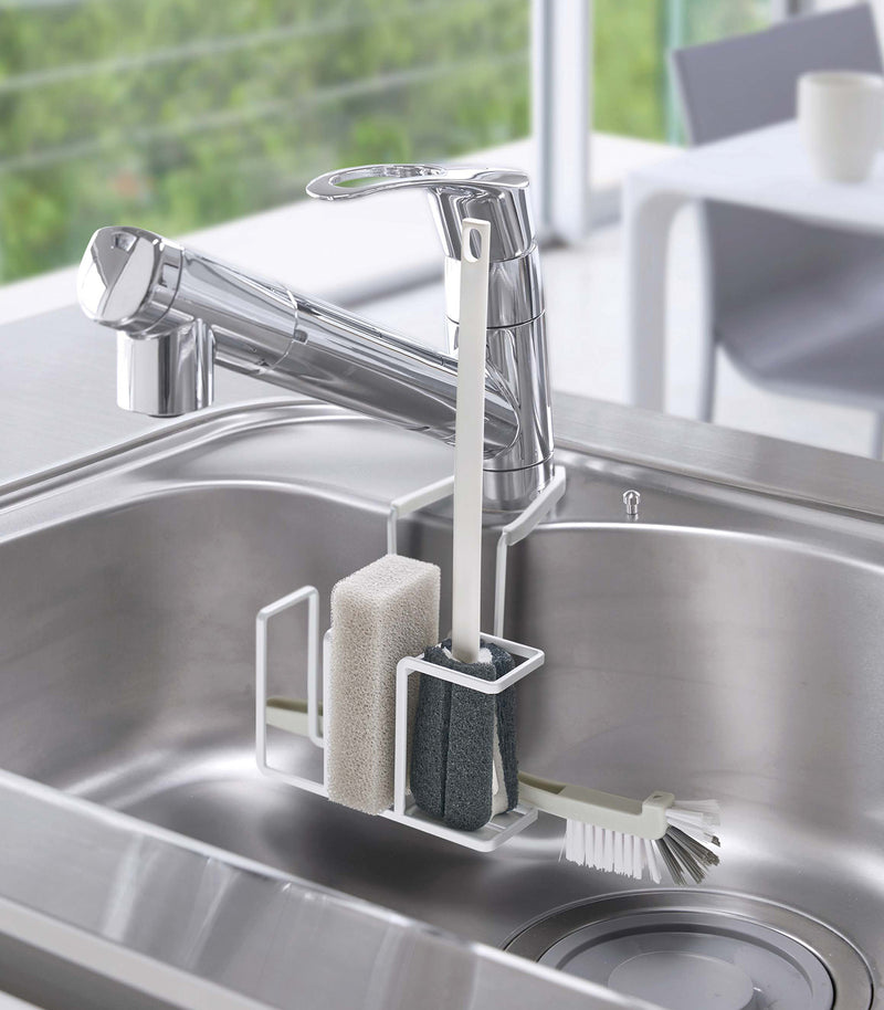 White Steel Yamazaki Home Faucet-Hanging Sponge & Brush Holder with a sponge and two brushes stored