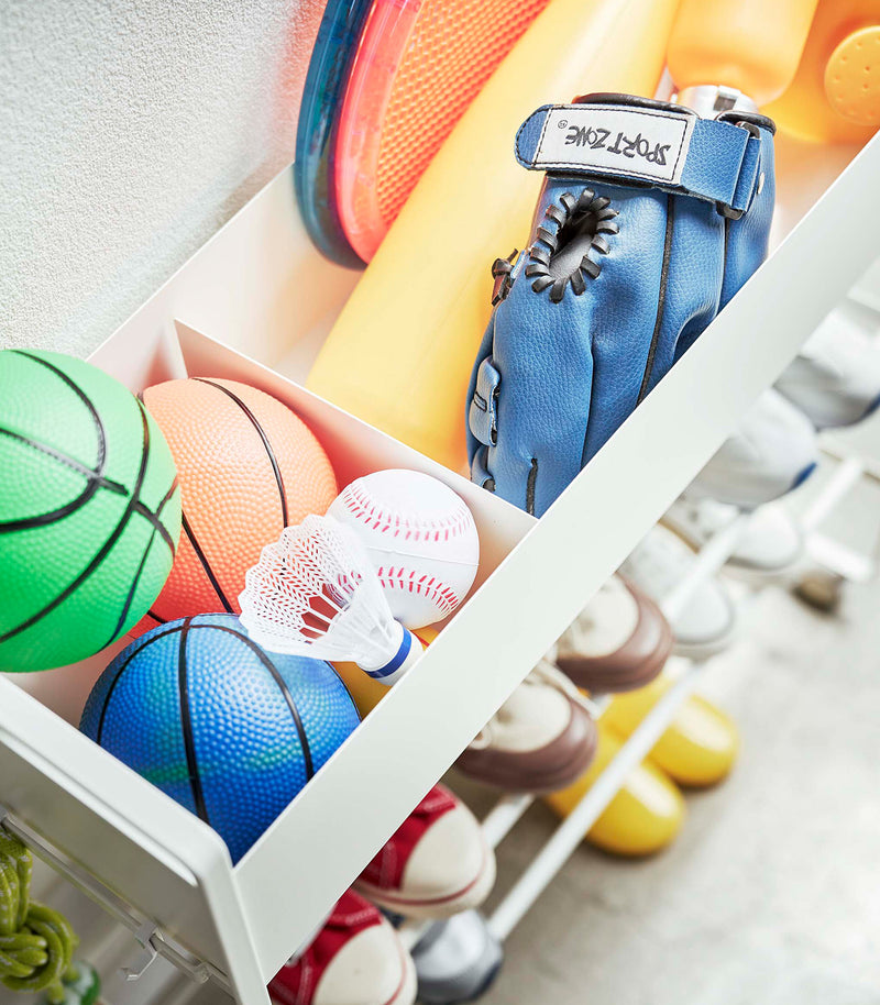 Close up top-down view of white Yamazaki Entryway Organizer with shoes and toys on it