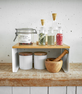 Front view of white Stackable Countertop Shelf on kitchen shelf holding spices and ingredients by Yamazaki Home. view 12