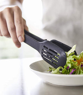 Close up view of black Floating Slotted Tongs serving salad by Yamazaki Home. view 23