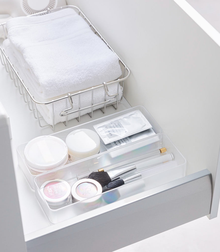 View 34 - Two large stackable clear organizers are placed in a bathroom drawer, organizing cosmetic items and brushes, neatly placed next to each other.