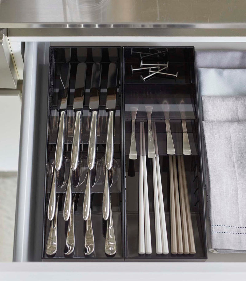 Aerial view of two black Cutlery Storage Organizers holding utensils in kitchen drawer by Yamazaki Home.