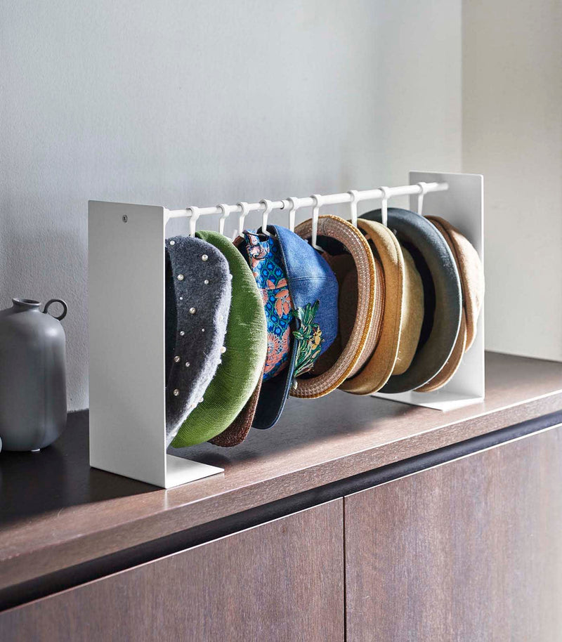 Expanded white Yamazaki Home hat rack hanging a variety of hats