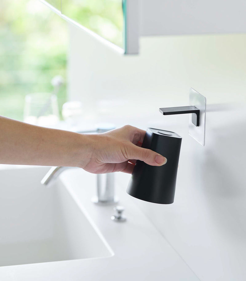 Removing white Yamazaki Home traceless adhesive magnetic cup installed next to sink
