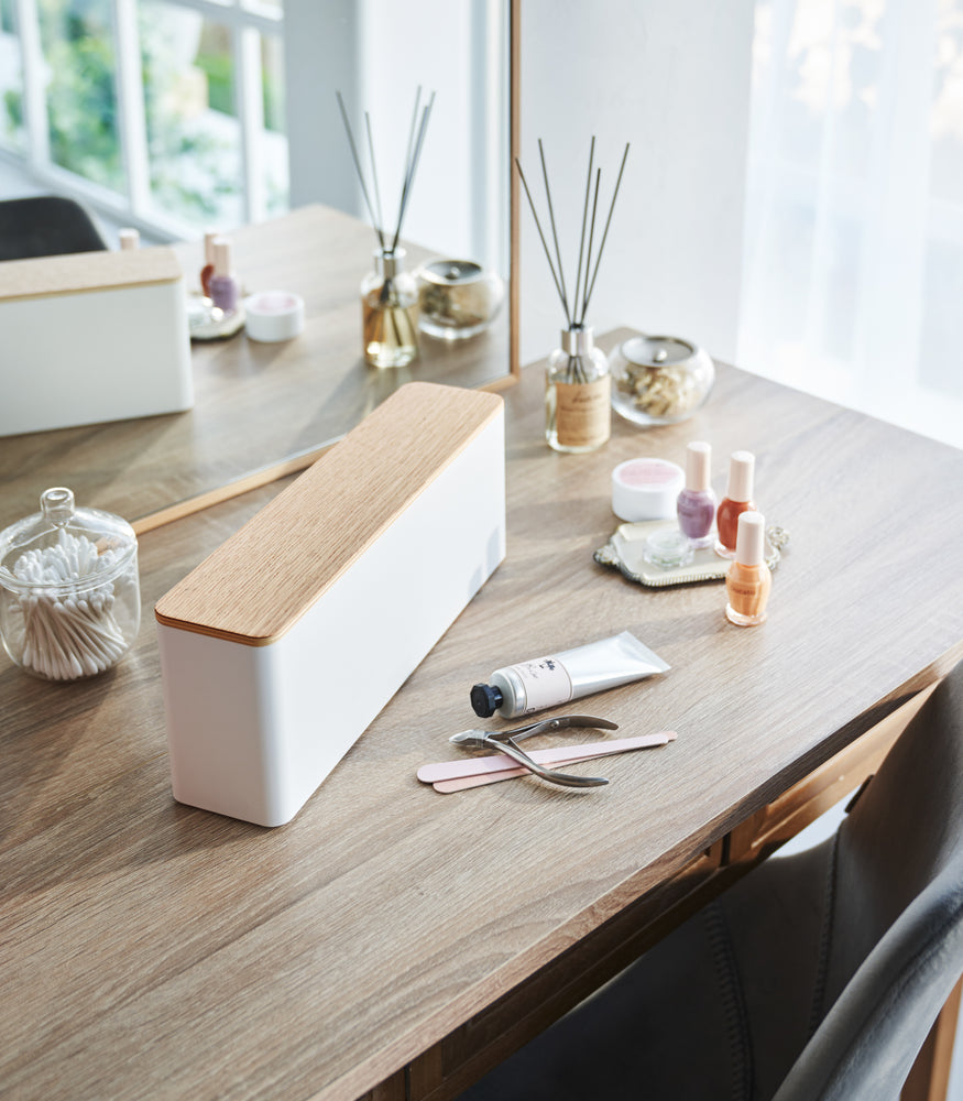 View 3 - A Yamazaki Nail Polish Organizer with a wooden top sitting on a table near various nail accessories.