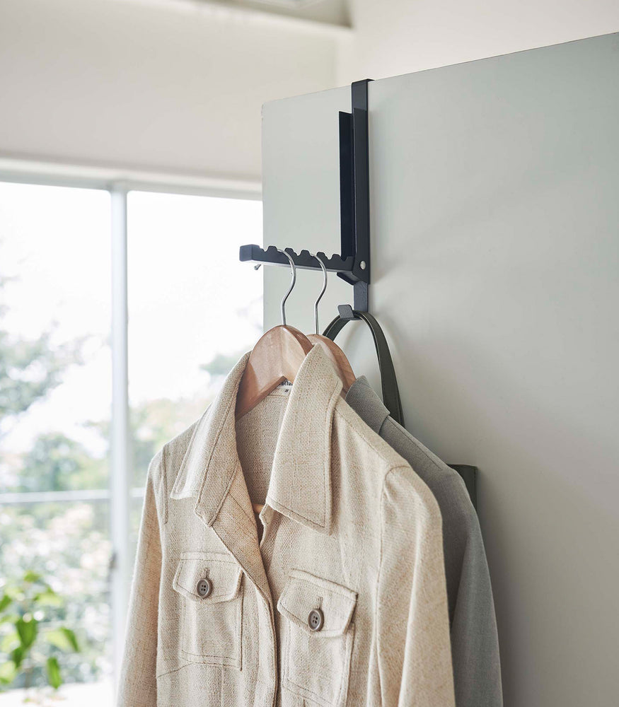View 10 - White Yamazaki Home Folding Over-The-Door Hanger opened with jackets hung
