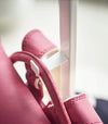 Close up view of white Rolling Coat Rack hook holding pink backpack by Yamazaki Home.