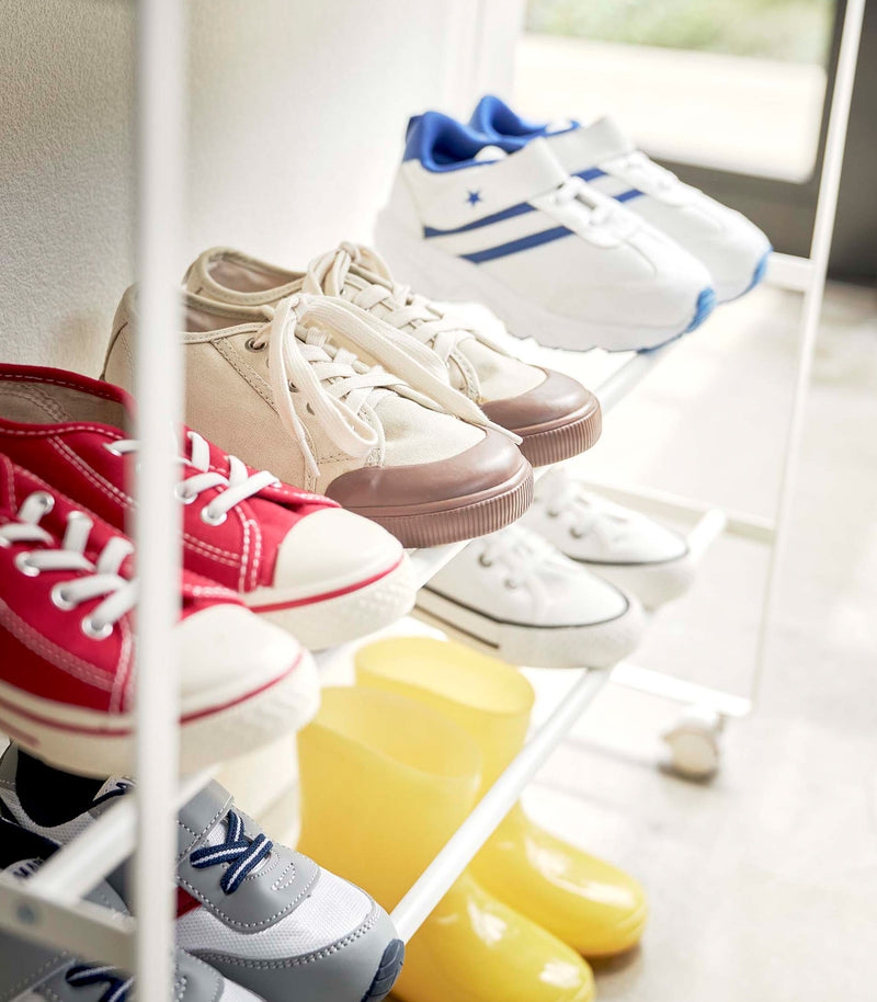 Close up side view of white Yamazaki Entryway Organizer with shoes on it