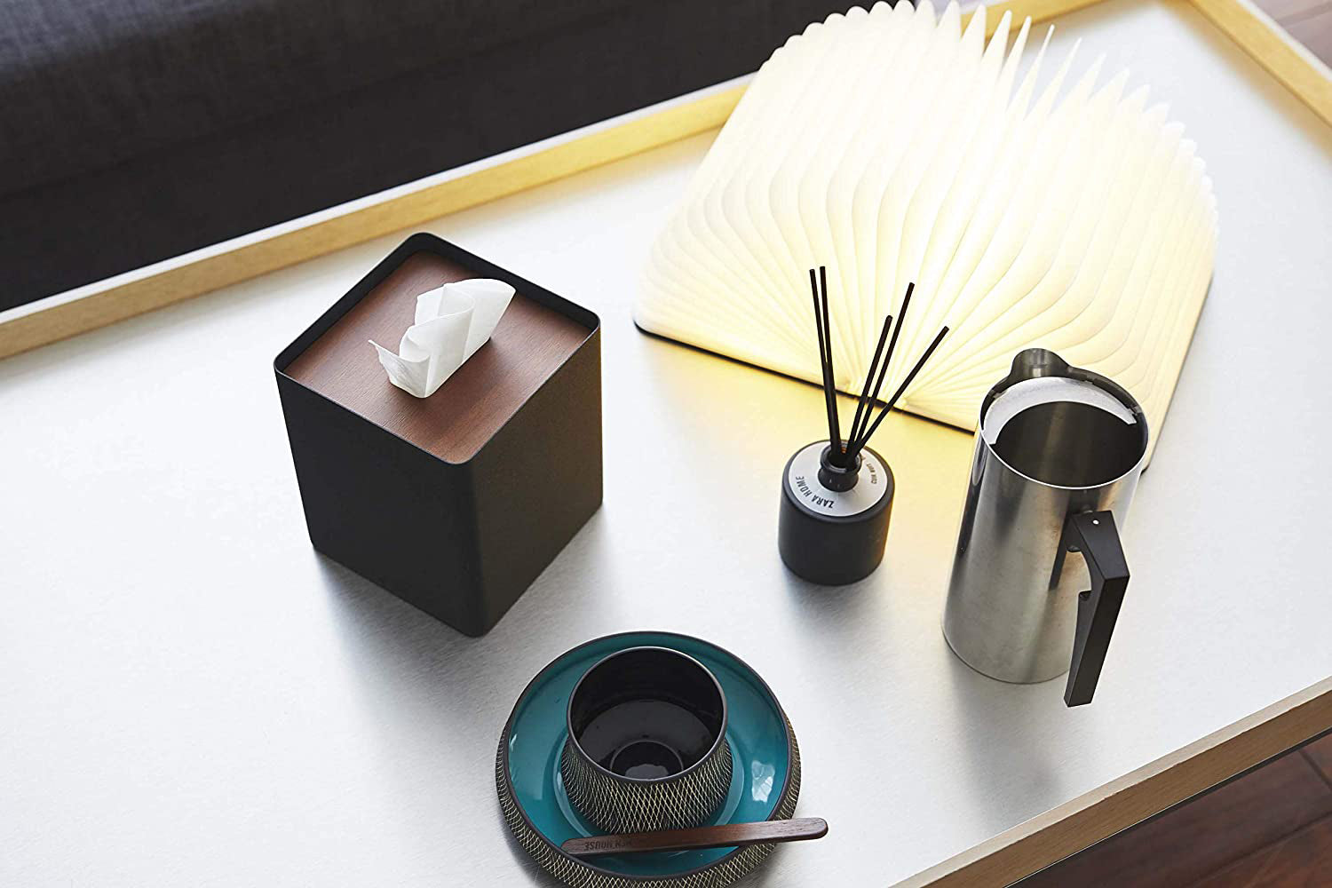 View 13 - Aerial view of black Tissue Case on table next to book light, cup, and décor pieces by Yamazaki Home.