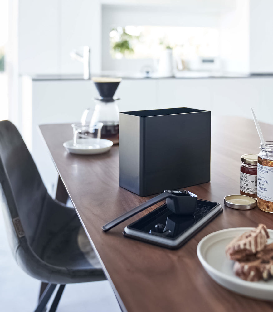 View 15 - Black Yamazaki Home kitchen storage box with a open lid on dining table with measuring spoon