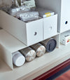 White Yamazaki Home Shelf Risers in a cabinet containing water bottles