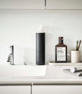 Small black Yamazaki Home Round Tissue Case on a bathroom sink counter view 15