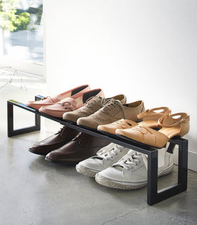 Black Expandable Shoe Rack holding in entryway holding shoes by Yamazaki home. view 8