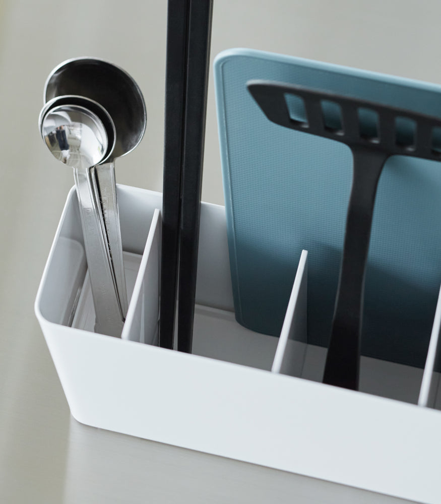 View 6 - Close-up of a White Utensil & Thin Cutting Board Holder by Yamazaki Home containing a blue cutting board and black utensils.