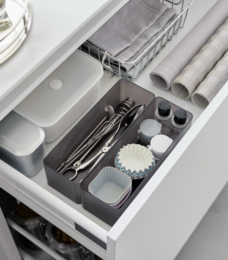 View 57 - Two deep stackable clear organizers in balck are placed in a bathroom drawer, organizing makeup tools and small bottles, neatly placed next to each other.