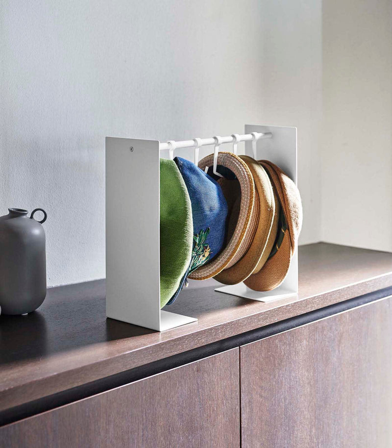 Shortened white Yamazaki Home hat rack hanging a variety of hats