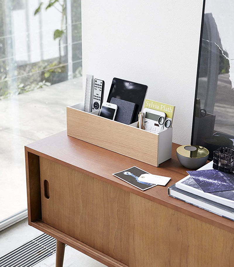 White Desk Organizer holding office items on tv stand by Yamazaki Home.