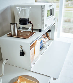 Side view of white Yamazaki Home Bread Box - Wide on a counter with a toaster and coffee equipment on top view 6