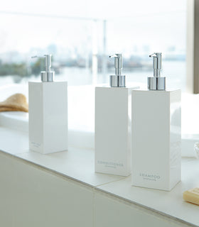 White Yamazaki Home soap dispenser in three styles by bathtub view 2