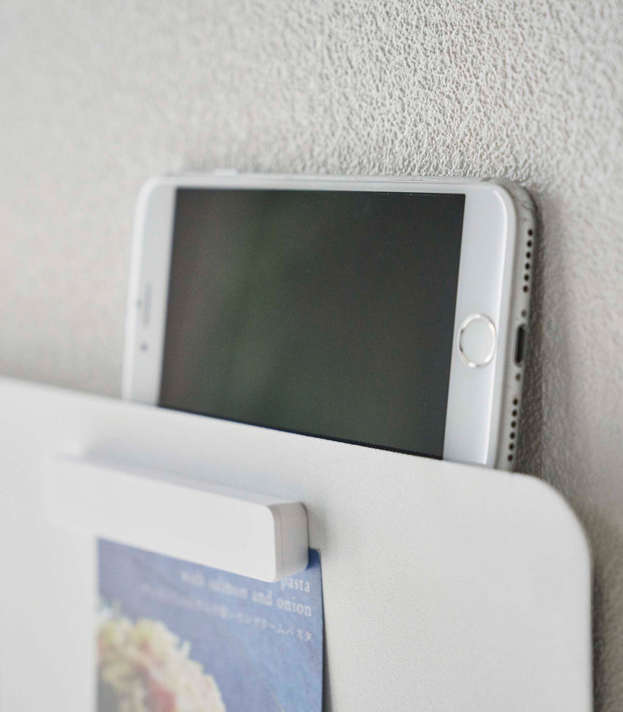View 6 - Closeup of a phone resting on top of a Yamazaki white Magnetic Wall Panel