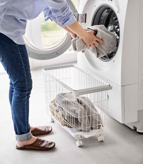 A person unloading laundry from a dryier into the Rolling Wire Basket by Yamazaki Home in white. view 8