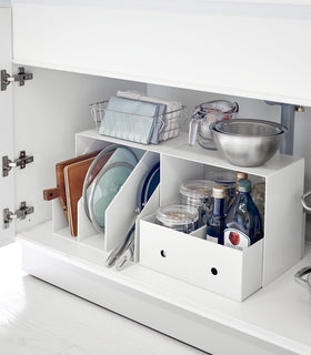 Side view of White Under-Cabinet Storage Shelves holding bowls and baskets on the top and oils and pans underneath under a sink. view 2