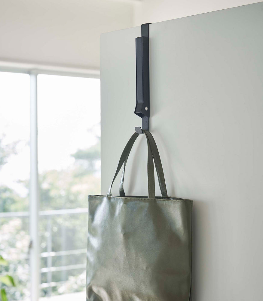 View 21 - Black Yamazaki Home Folding Over-The-Door Hanger closed with a purse hung