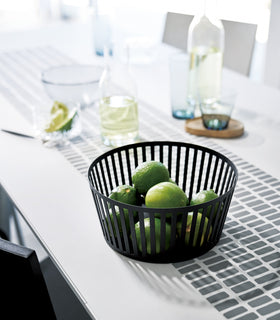 Black Fruit Basket holding limes on dining room table by Yamazaki Home. view 6