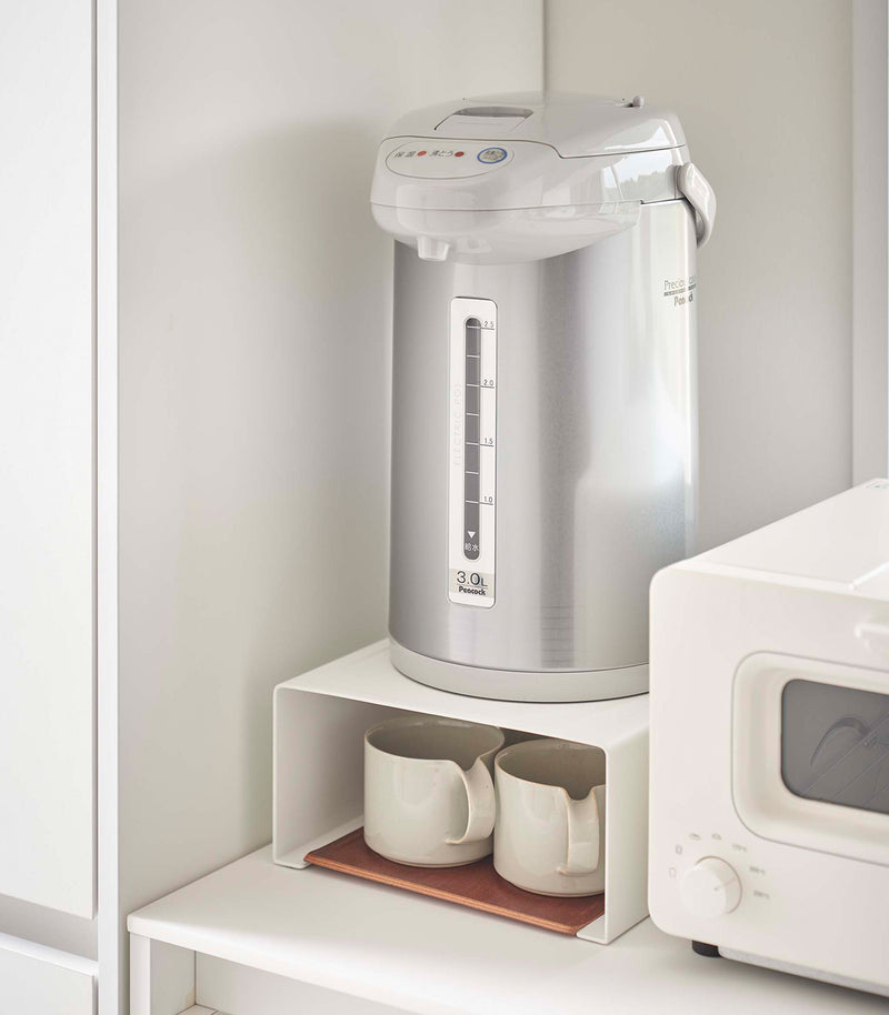 White Yamazaki Home Stackable Countertop Shelf with cups below and a water dispenser above